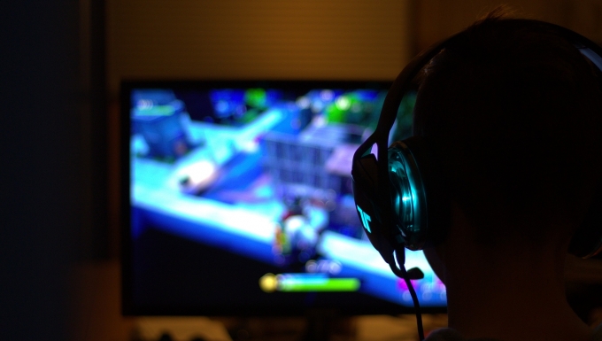 Une personne de dos jouant dans la pénombre à un jeu vidéo. 