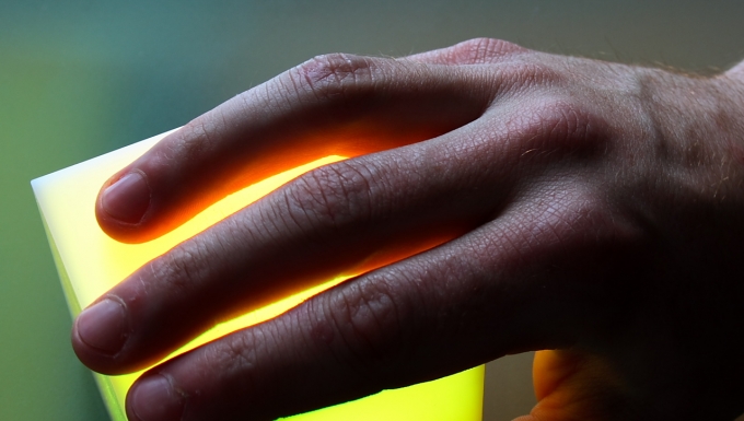 Une main posée sur un carré luminescent.