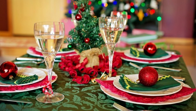 Une table de fête, avec des assiettes, flûtes à champagne et décorations. Un sapin en arrière-plan