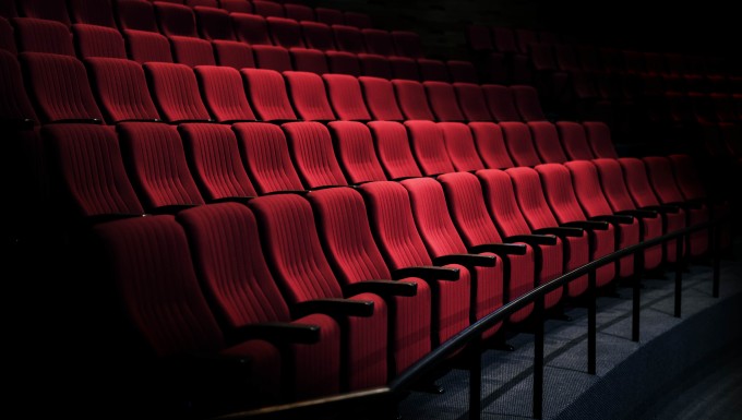 Photo couleur de rangées de sièges de couleur rouge dans une salle de cinéma.