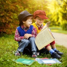 Deux enfants lisant ensemble des livres sur le bord d'une route ensoleillée à la campagne.