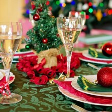 Une table de fête, avec des assiettes, flûtes à champagne et décorations. Un sapin en arrière-plan