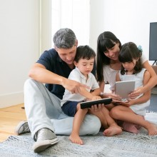Photo d'une famille réunie autour de tablettes numériques.