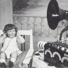 Photo en noir et blanc d'un enfant écoutant avec un casque un poste radio dans les années 30.