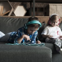Deux enfants dans un canapé avec tablettes et casques audios