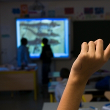 Main levée d'un élève dans une salle de classe pour répondre à une question