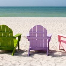Une série de fauteuils en bois de plusieurs couleurs alignés sur la palge