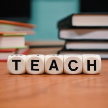 Dés marqués d'une lettre formant le mot "Teach" sur un bureau d'une salle de classe