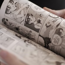 Photo rapproché d'un manga dont les pages sont tournées par un lecteur.