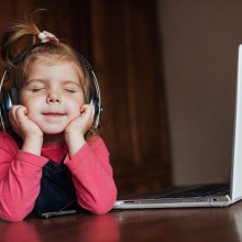 Photo couleur d'une petite fille écoutant du contenu audio avec un casque.